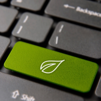 Green energy button on laptop keyboard with leaf icon, symbolizing environmental awareness and sustainability.